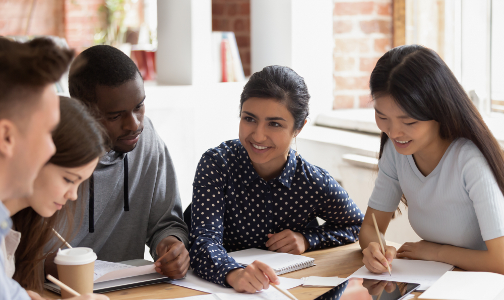 Focused multi national students sitting at desk studying together
